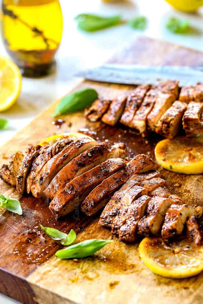 showing how to make lemon chicken pasta by slicing chicken on a cutting board