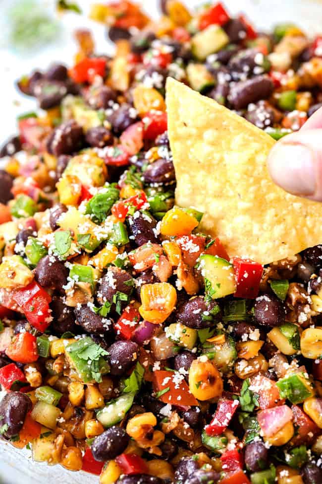 a tortilla chip dipping into black bean and corn salsa recipe
