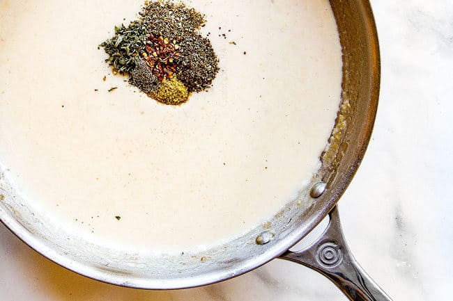 showing how to make chicken spaghetti by adding seasonings to chicken spaghetti sauce