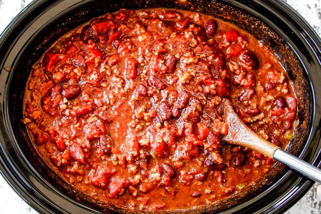 showing how to best crockpot chili recipe by stirring all the ingredients in the slow cooker