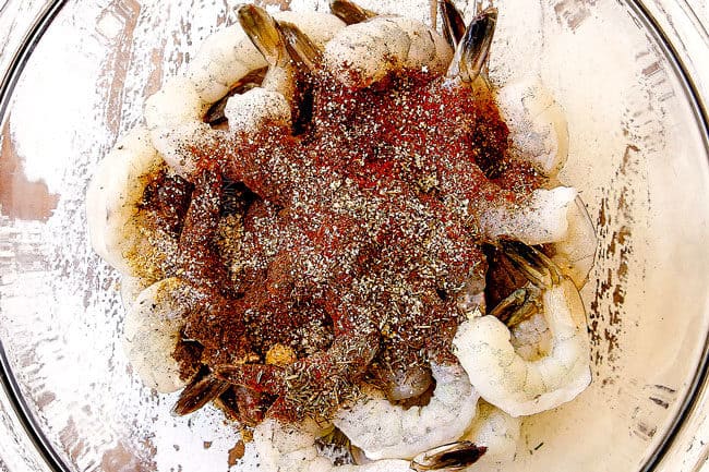 showing how to make shrimp avocado salad recipe by adding seasonings to shrimp