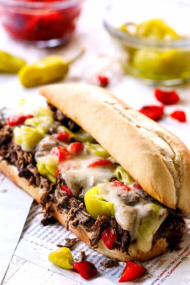 showing how to make Italian Beef Sandwich recipe by melting cheese over Italian Beef and toppings