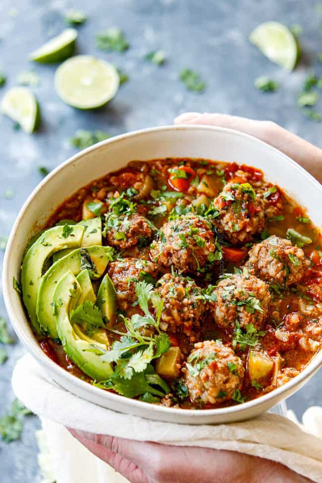 two hands holding a bowl of best Albondigas Soup