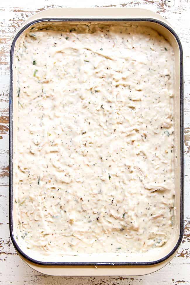 showing how to make spinach chicken lasagna by finishing layering lasagna with top layer of chicken Alfredo sauce