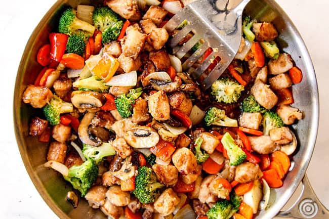showing how to make easy chicken stir fry recipe by adding chicken and chicken stir fry sauce to vegetables in skillet