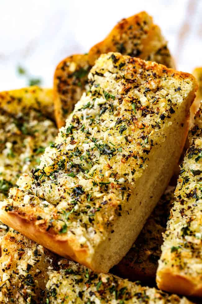 up close of a piece of the best garlic bread recipe in a bowl garnished with parsley