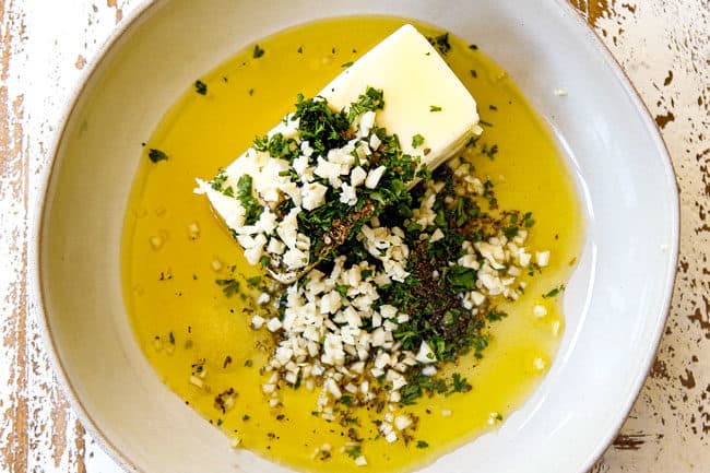 showing how to make garlic bread by adding butter, olive oil, garlic and herbs to a bowl for garlic butter spread