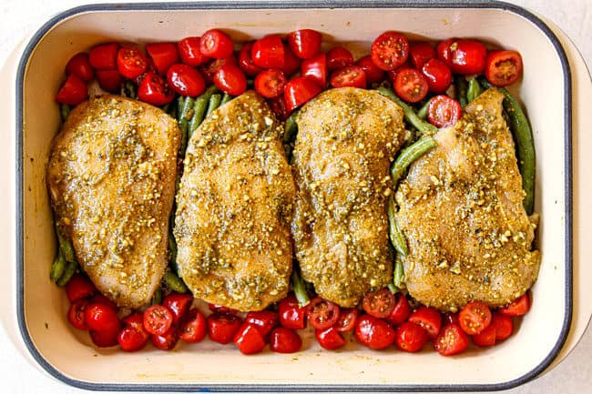 showing how to make pesto chicken recipe by lining tomatoes on sides of tomatoes