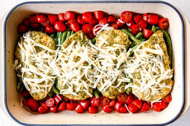 showing how to make pesto chicken bake by adding cheese on top of chicken