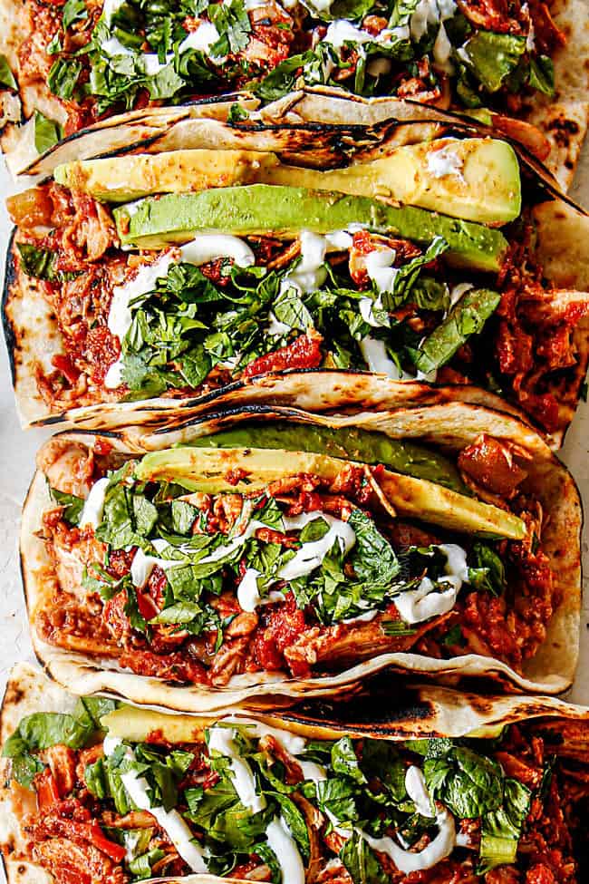 showing how to make shredded chicken tacos by adding toppings