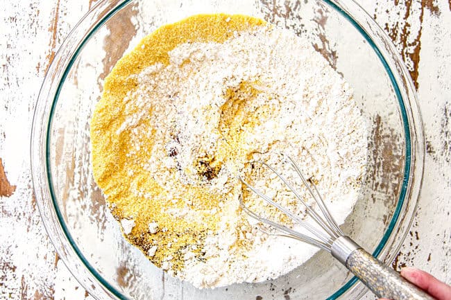 showing how to make corn casserole recipe by mixing cornmeal, flour, salt and baking powder together in a glass bowl