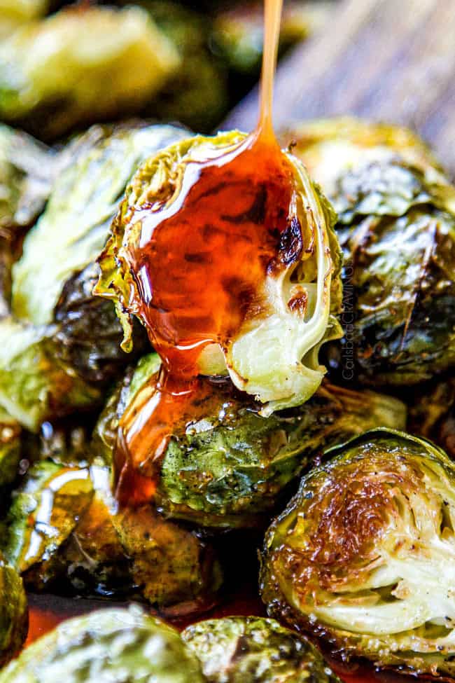 showing how to cook Brussels Sprouts recipe in oven by drizzling honey sriracha over oven Roasted Brussels Sprouts