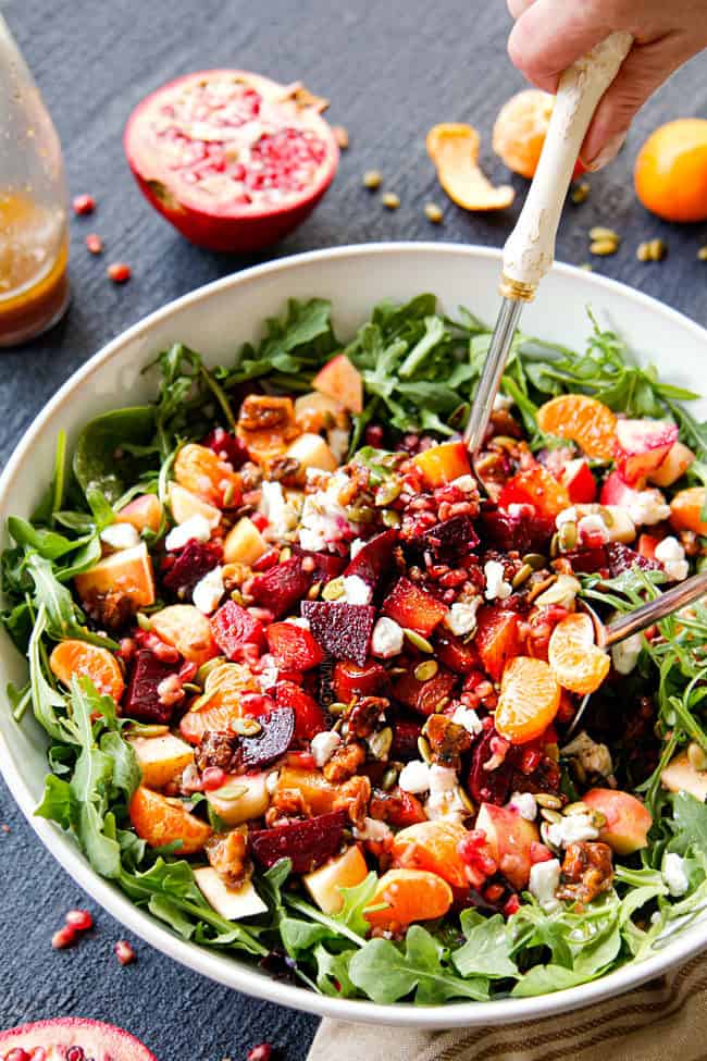 tossing roasted beet salad recipe together in a large white bowl