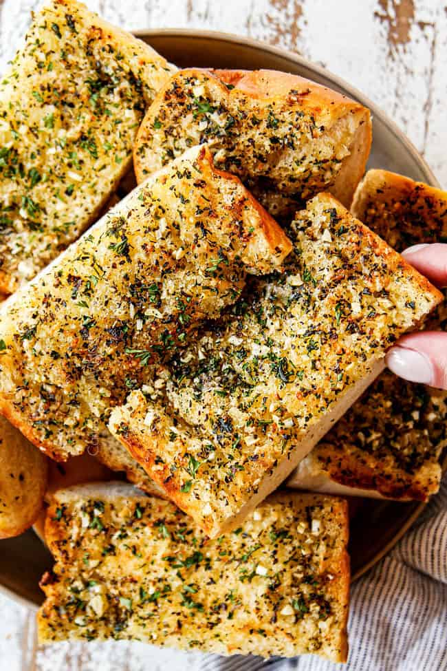 a hand taking a slice of garlic bread in oven