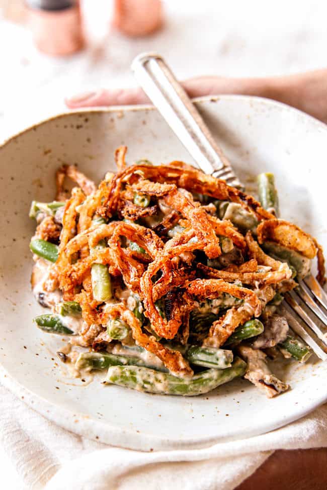 two hands holding a plate of green bean casserole from scratch