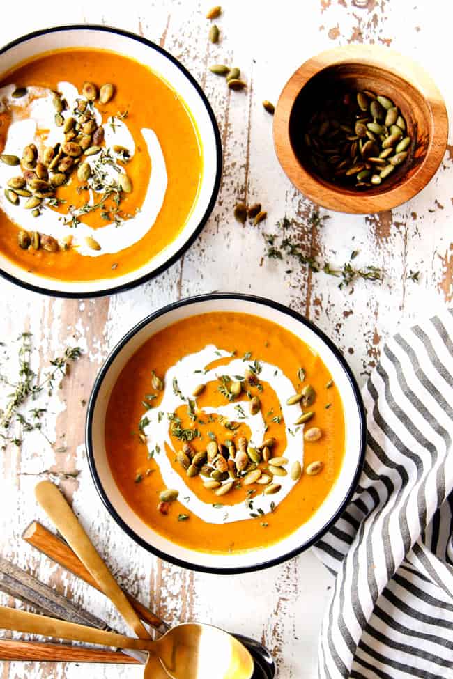 top view of two bowls of easy butternut squash soup garnished with pumpkin seeds and heavy cream