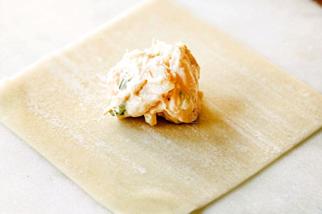 showing how to make crab rangoon by adding filling to center of wonton wrapper