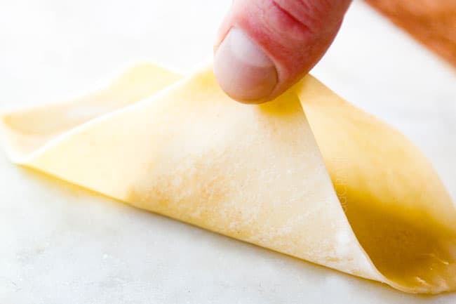 showing how to make crab rangoon by bringing to corners of wonton together and pinching to seal