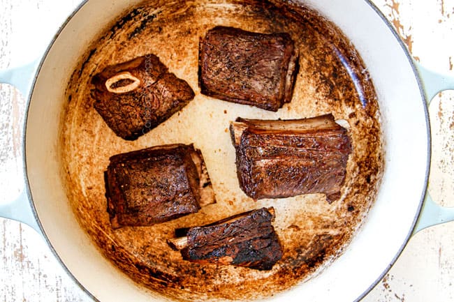showing how to make short ribs by searing short ribs in a Dutch oven