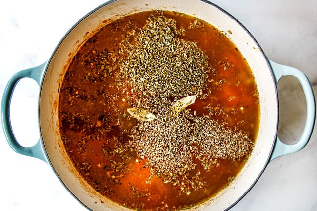 showing how to make easy chicken noodle soup by adding chicken broth, parsley, basil, oregano, thyme, bay leaves, salt and pepper