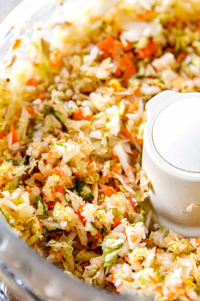 showing how to make egg rolls by adding vegetables to food processor to chop