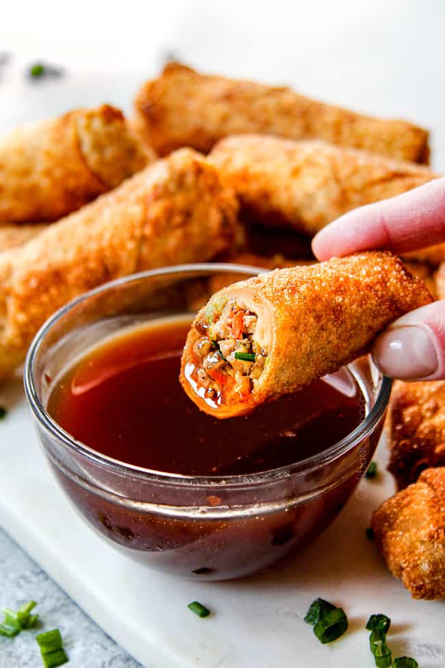showing how to eat pork egg rolls by dipping into dipping sauce