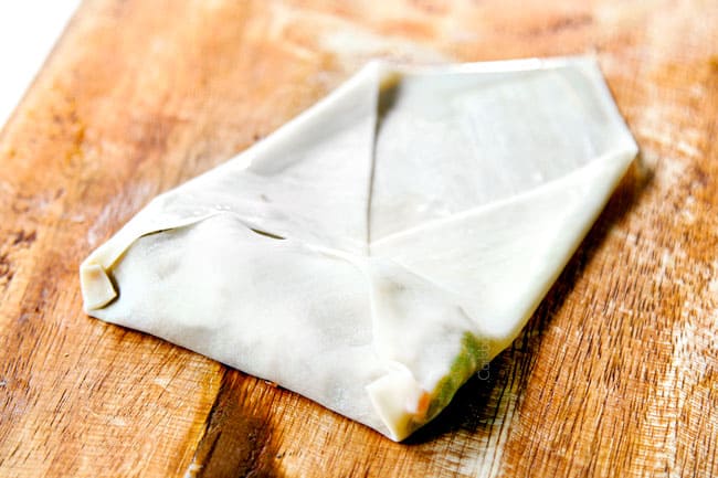 showing how to make easy egg rolls by folding corners into the center over the filling