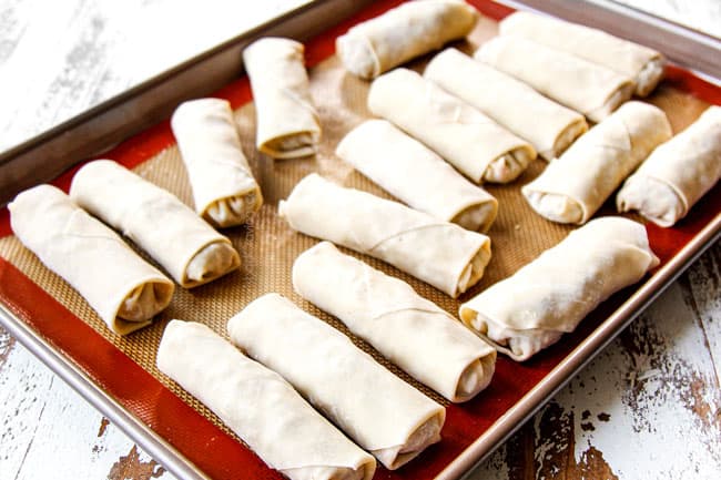 showing how to make homemade egg rolls by storing on a nonstick mat until ready to fry