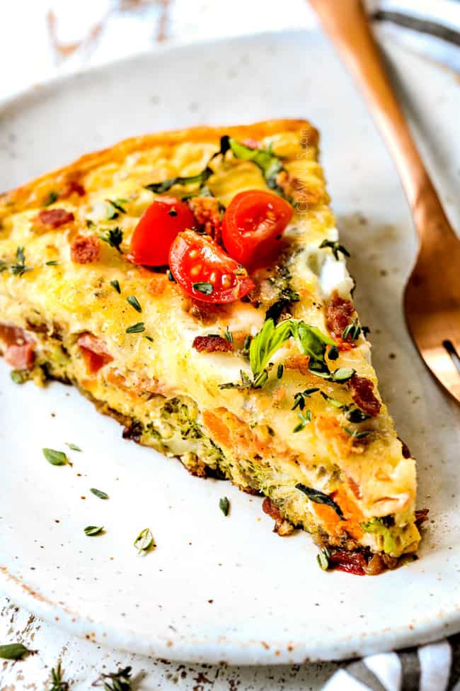 showing how to serve frittata recipe by placing a slice on a plate and garnishing with basil and tomatoes