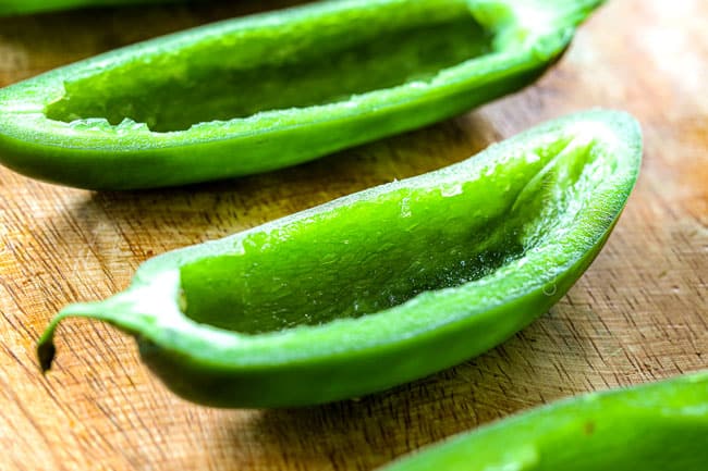 showing how to make best jalapeno poppers by lining hollow jalapenos on a cutting board