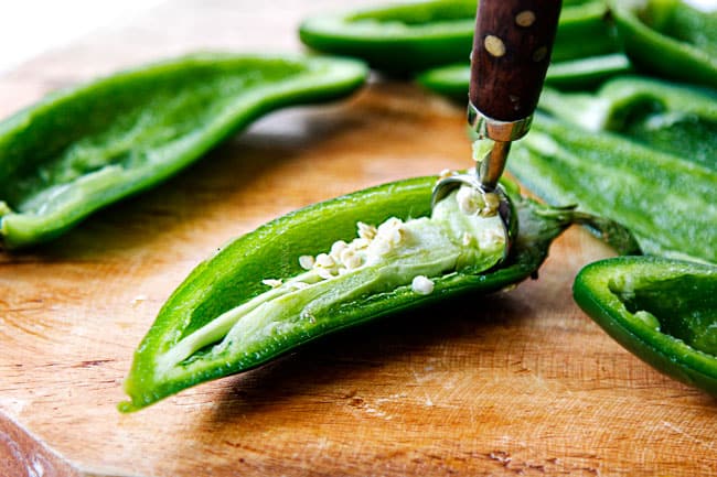 showing how to make easy jalapeno poppers by removing the seeds and ribs using a teaspoon