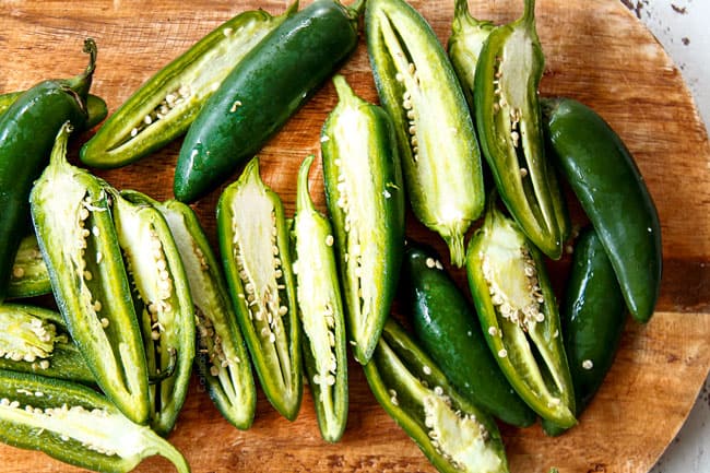 showing how to make baked jalapeno poppers by cutting jalapenos in half from stem to end