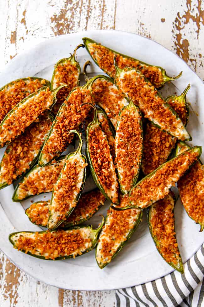 showing how to serve homemade jalapeno poppers by placing on a plate with dip