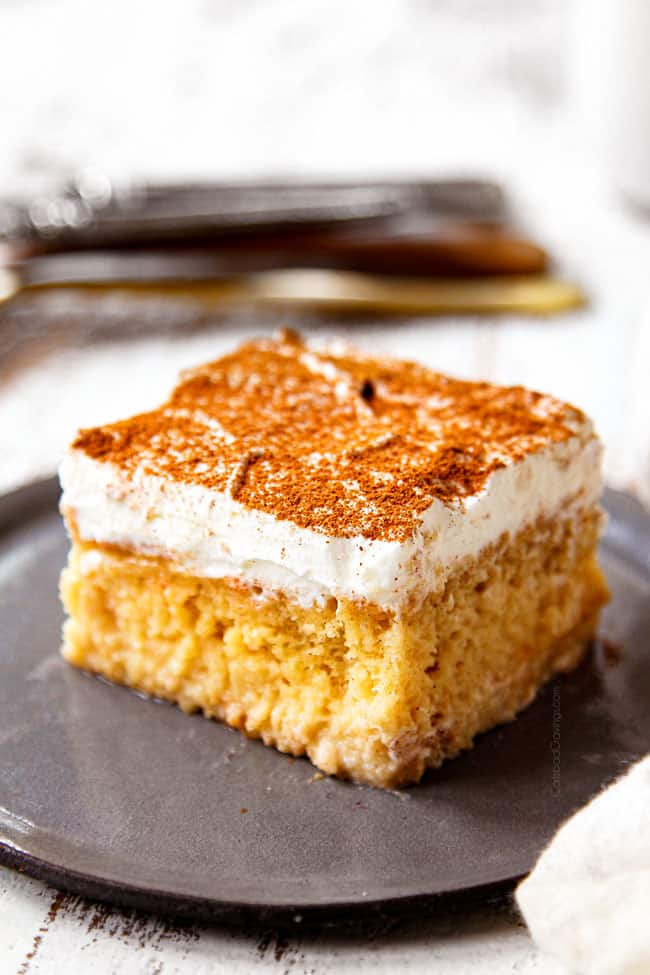 showing how to serve authentic tres leches cake by dusting a slice with cinnamon