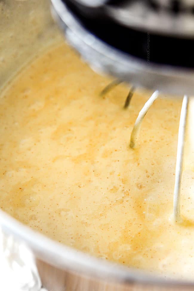 showing how to make tres leches cake by mixing flour into wet ingredients