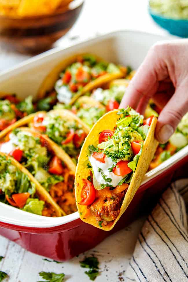 a hand holding a baked beef taco showing how easy they are to serve
