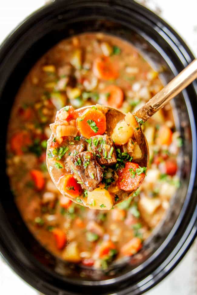 showing how to make crockpot beef and barley soup by adding beef broth to adjust consistency