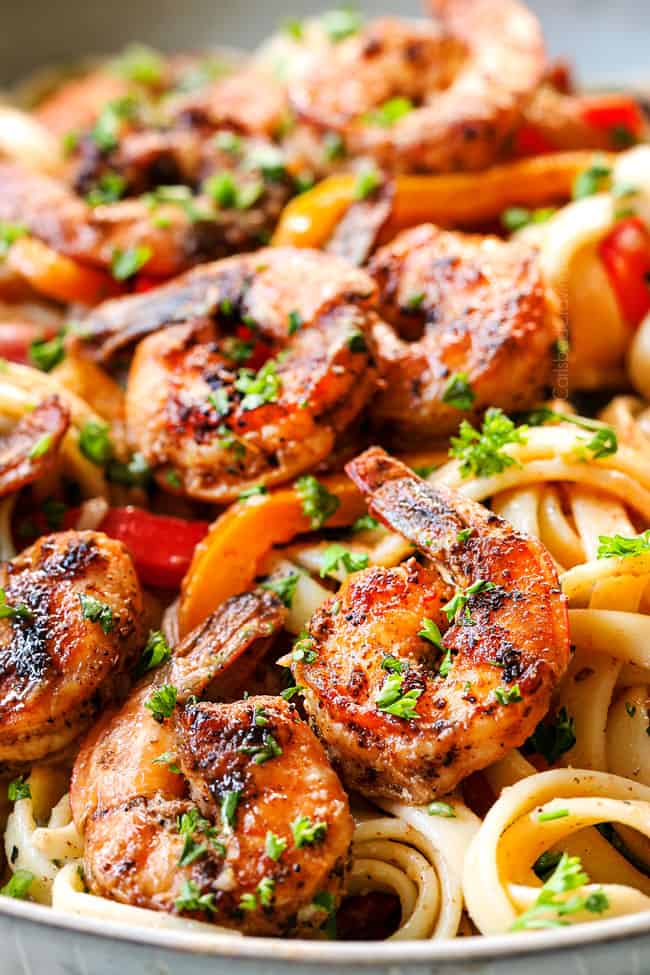 up close of Alfredo Cajun Shrimp Pasta recipe with shrimp, bell peppers, red onion, parsley and Parmesan