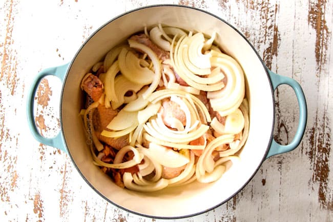 showing how to make chicken tinga by adding a whole chicken to a Dutch oven to cook and shred