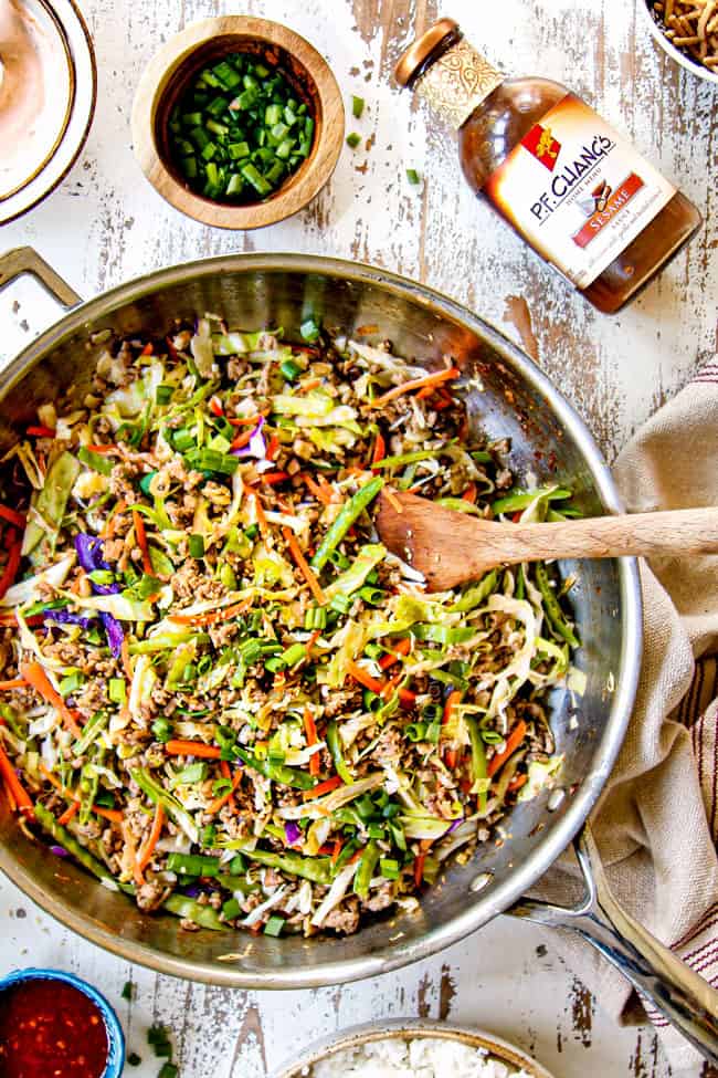 showing how to make egg roll in a bowl garnishing with green onions and sesame seeds in a skillet