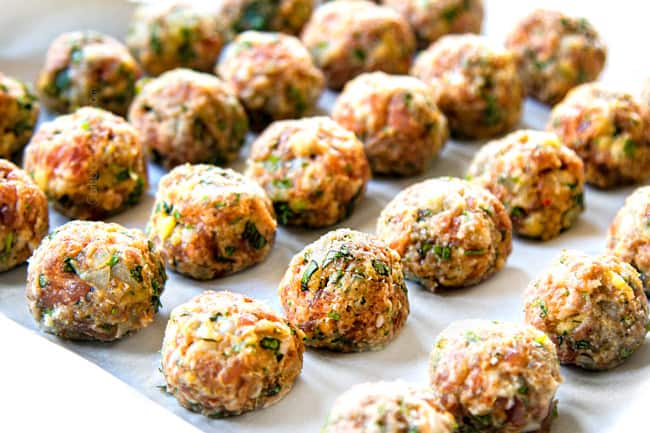 showing how to make Italian Meatball Soup by rolling ground beef, pork and herbs into meatballs and lining in rows on parchment paper