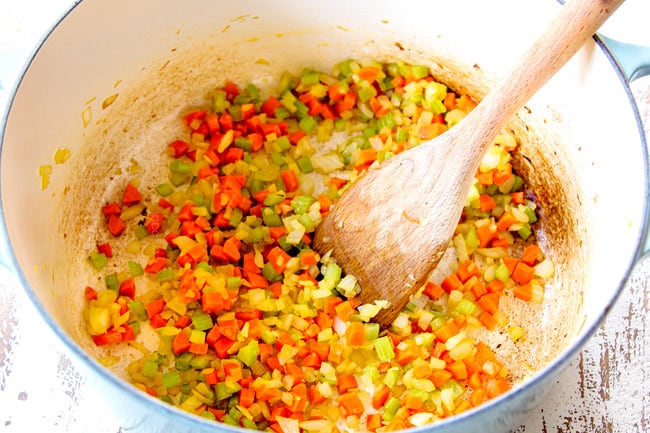 showing how to make Italian Meatball Soup by sauteing carrots, onions and celery in a white Dutch oven
