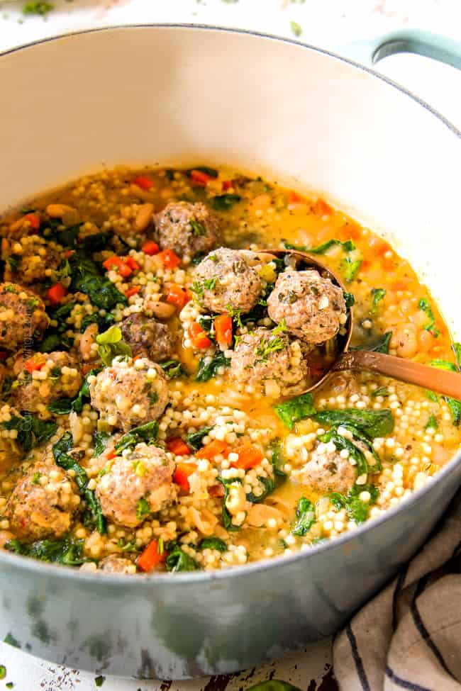 showing how to serve easy Italian Meatball Soup recipe by scooping a big spoonful of soup in a brass ladle