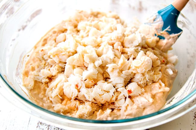 showing how to make crab dip by adding lump crab m eat to a glass bowl with cream cheese base