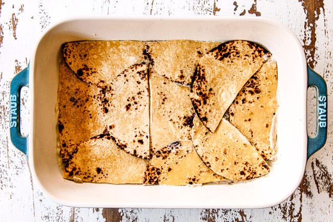 showing how to make green chicken enchilada casserole recipe by layering corn tortillas over enchilada sauce