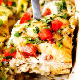 up close of serving chicken enchilada casserole recipe with a slice on a silver spatula