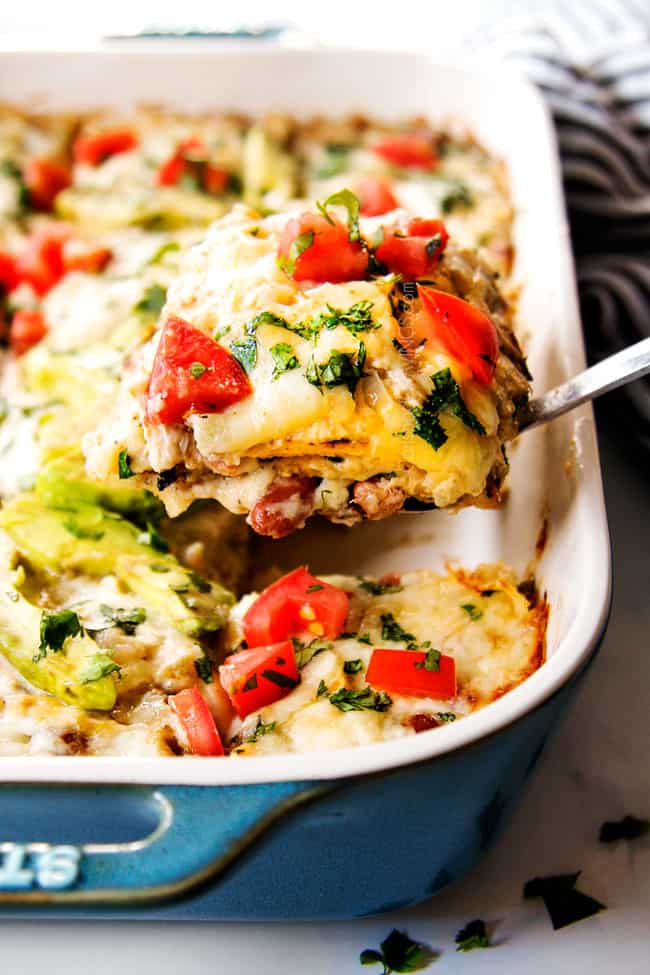 showing the layered sides of easy chicken enchilada casserole by holding up a slice on a spatula