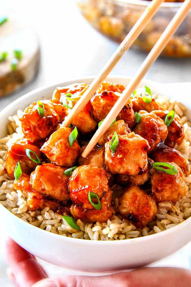 showing how to eat easy orange chicken by picking up orange chicken with chopsticks
