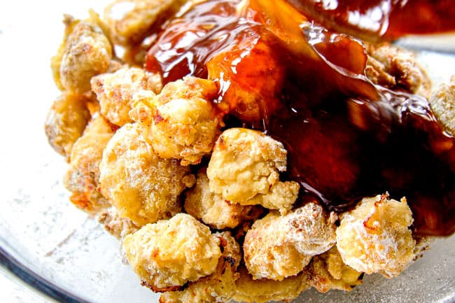 showing how to make homemade orange chicken by pouring orange sauce over chicken