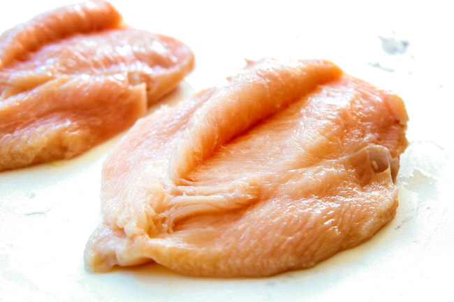 showing how to make chicken piccata recipe by slicing chicken in half through the equator